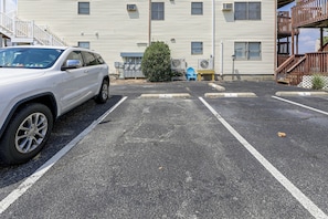 A parking lot with a white SUV parked in a space. There are multiple air conditioning units mounted on the building behind. - Bayside Waterfront OC Sleeps 8 | Beach | Boardwalk (Ocean City)