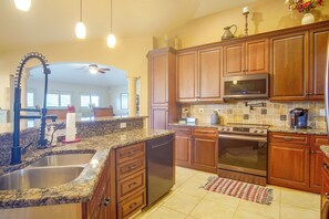 A kitchen with granite countertops, wooden cabinets, a stainless steel sink, a built-in oven, and a microwave. - Private Yard w/ Fire Pit & Pool! Cape Coral Escape (Cape Coral)