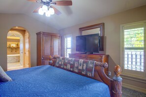 A bedroom with a large bed, a television, a wooden wardrobe, and a ceiling fan. - Private Yard w/ Fire Pit & Pool! Cape Coral Escape (Cape Coral)