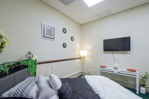A bedroom with a bed, bedside table, lamp, TV, and decorative items.