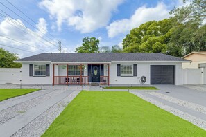 Ein einstöckiges Haus mit Veranda, Garage und einem gepflegten Rasen.