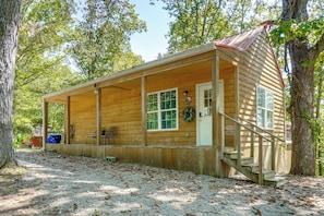A wooden cabin with a porch, a door, and a window.
