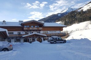 En trælodge med skiltet 'Brugghof' i et snæhreget, bjergrigt område.