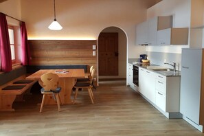 Eine moderne Küche mit weißen Schränken, einem Holzesstisch und einer Bank.