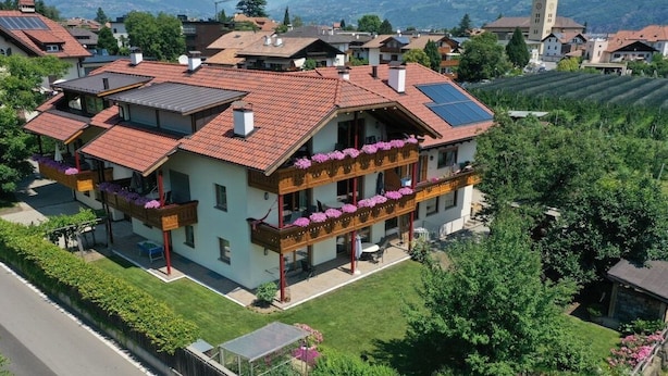 Un edificio residencial de varios pisos con balcón, paneles solares y jardín.