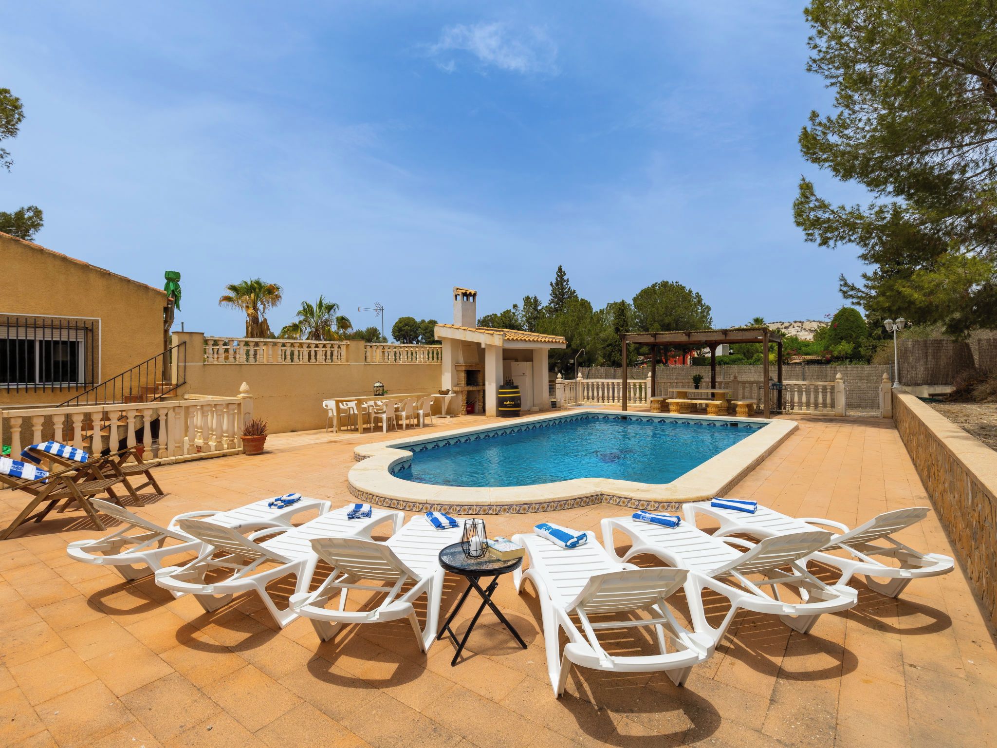 Une piscine avec des chaises longues et une pergola.