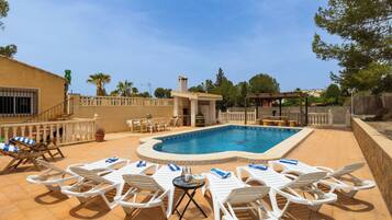 Une piscine avec des chaises longues et une pergola.