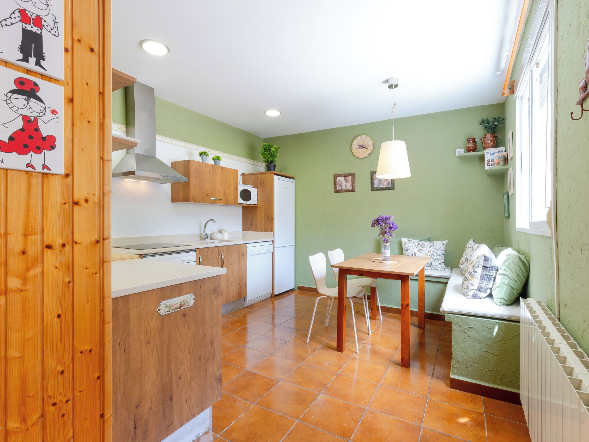 Une cuisine compacte avec des meubles en bois, un four encastré et un coin repas comprenant une table et des chaises.