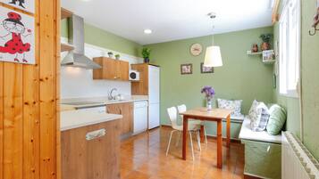 Une cuisine compacte avec des meubles en bois, un four encastré et un coin repas comprenant une table et des chaises.