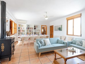 Un salon avec une cheminée, un canapé, une table basse et un coin repas comprenant des chaises et une table.