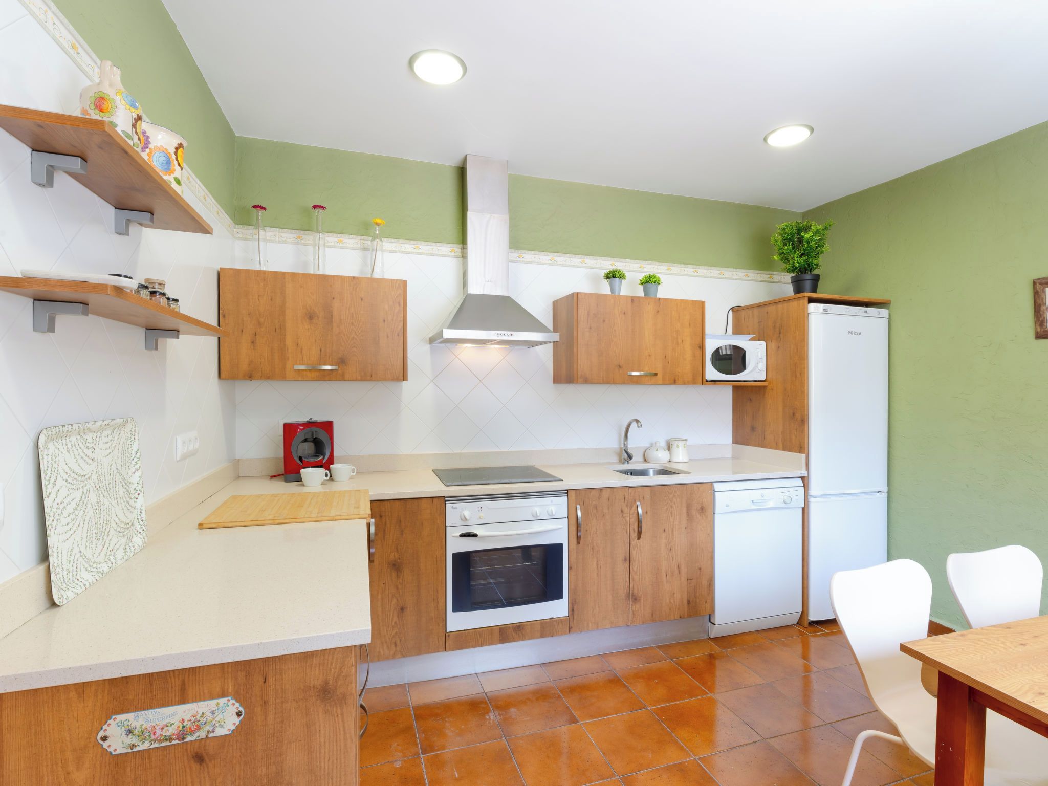 Une cuisine compacte avec des meubles en bois, un four encastré, un four à micro-ondes et un lave-vaisselle.