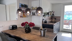 Eine moderne Küche mit einem Holztisch, einem Toaster, einer Vase mit roten Blumen und einer Champagnerflasche.