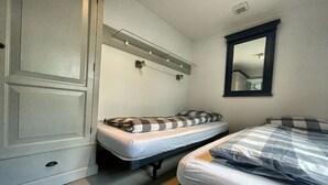 Et lille værelse med to senge, et skab, et spejl og en hylde med lys.