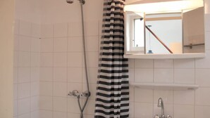 Ein Badezimmer mit Dusche, Waschbecken, Spiegel und einem gestreiften Duschvorhang.