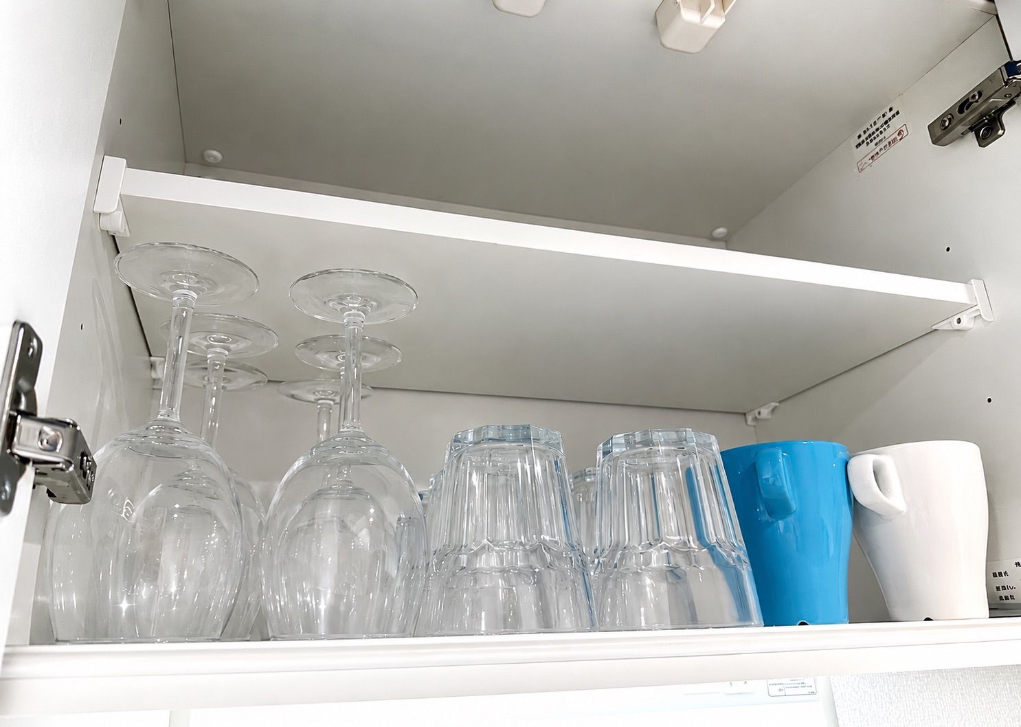 A storage compartment with wine glasses and a mug.