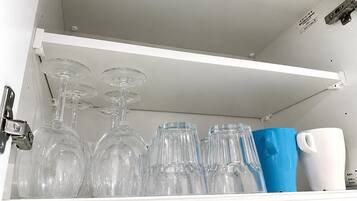A storage compartment with wine glasses and a mug.