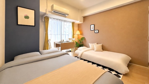 Una habitación de hotel con cama, mesita de noche, lámpara y ventana con cortinas.