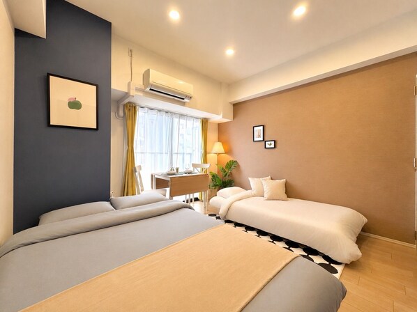 A hotel room with a bed, bedside table, lamp, and a window with curtains. - Vrbo Property (大阪市西区九条南3-19)