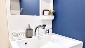 Un baño moderno con un lavamanos blanco, grifos cromados y un espejo arriba.
