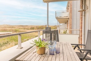 A wooden deck with a potted plant and two glasses, overlooking a grassy landscape. - Holiday apartment in Groote Keeten with Wi-Fi (Groote Keeten)