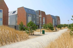 A modern building with a brick facade and large windows, surrounded by dry grass and a clear sky. - Holiday apartment in Groote Keeten with Wi-Fi (Groote Keeten)
