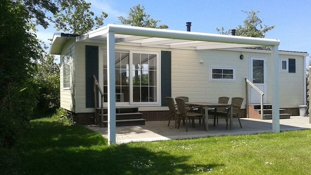 Une maison mobile de plain-pied dotée d’un patio couvert, d’une table à manger et de chaises.