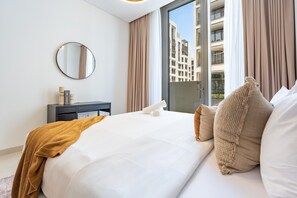 A hotel room with a large bed, a round mirror, a small bedside table, and a view of the city through a window. - Chic 1BR with Outdoor Terrace, Minutes from Downtown Dubai (Dubai)