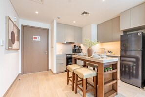 A modern kitchen with a built-in island, a black refrigerator, and a wooden door. - Chic 1BR with Outdoor Terrace, Minutes from Downtown Dubai (Dubai)
