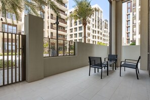 An outdoor patio area with a table and chairs, a gate, and a view of residential buildings. - Chic 1BR with Outdoor Terrace, Minutes from Downtown Dubai (Dubai)