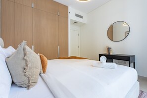 A hotel room with a bed, a bedside table, a mirror, and a wardrobe. - Chic 1BR with Outdoor Terrace, Minutes from Downtown Dubai (Dubai)