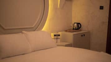 A hotel room with a bed, a nightstand, a coffee maker, and a cabinet.