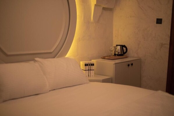 A hotel room with a bed, a nightstand, a coffee maker, and a cabinet. - HOTEL ESTARA (Şanlıurfa)