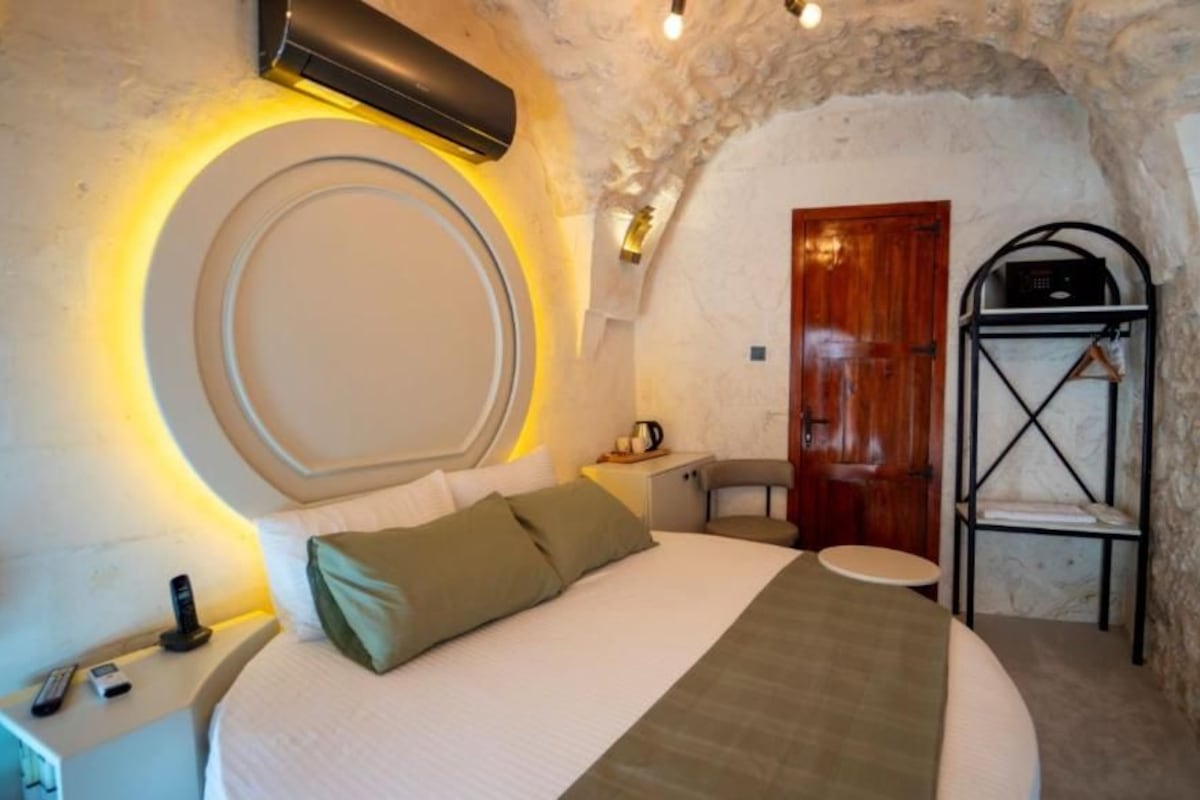 A bedroom with a bed, bedside table, lamp, and a wardrobe.