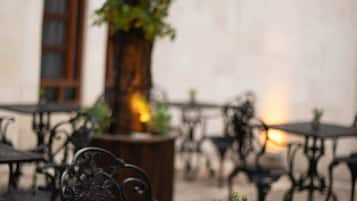 An outdoor seating area with tables and chairs, a tree, and a small potted plant.