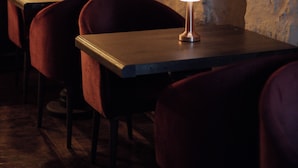 Una habitación tenuemente iluminada con paredes de piedra, una mesa y sillas.
