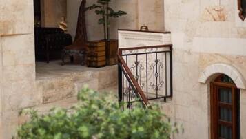 Un edificio de piedra con una entrada en arco, una escalera con barandilla de hierro forjado y un pequeño balcón con baranda.