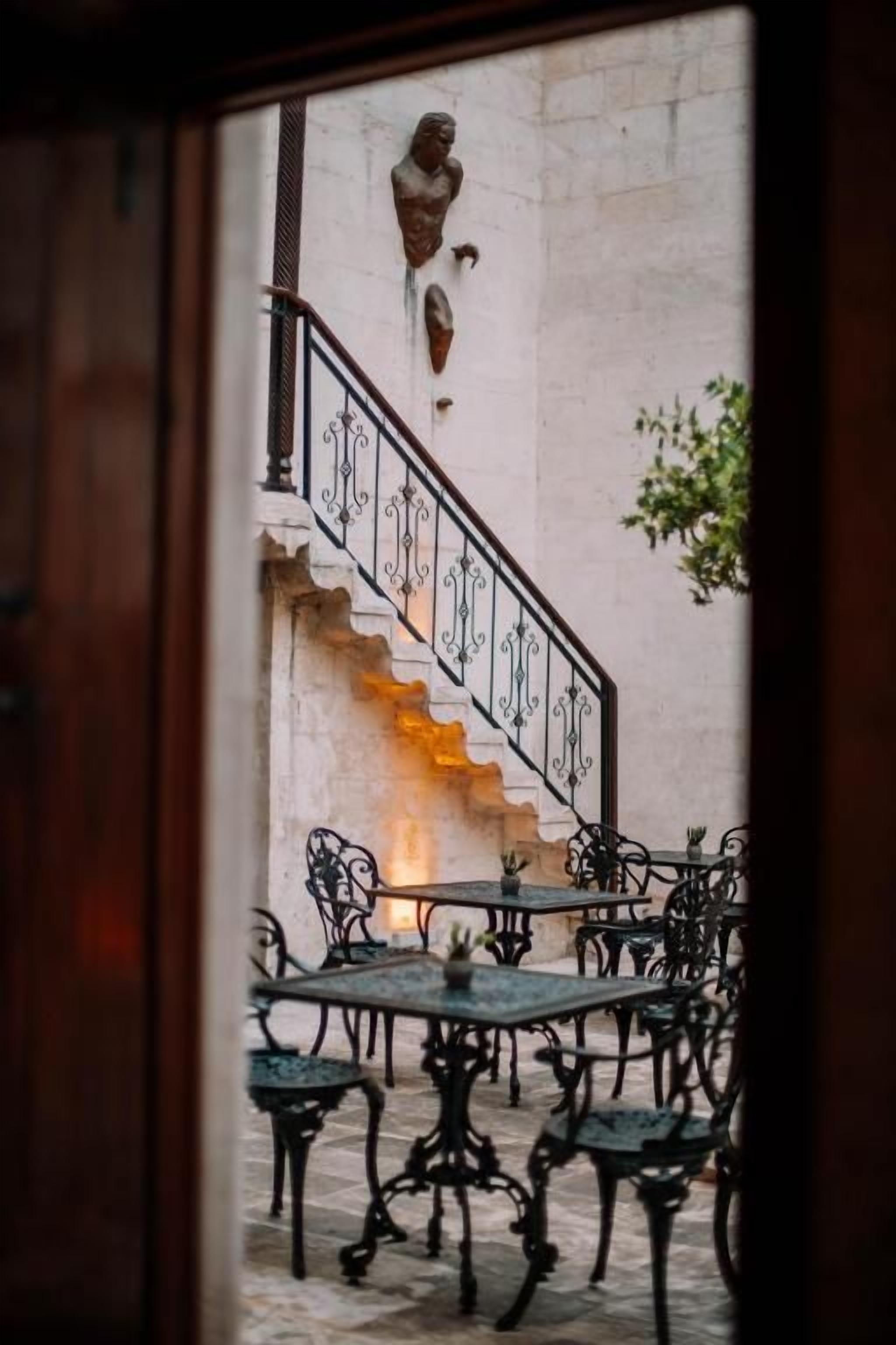 A staircase with ornate railings leading to a seating area with tables and chairs.