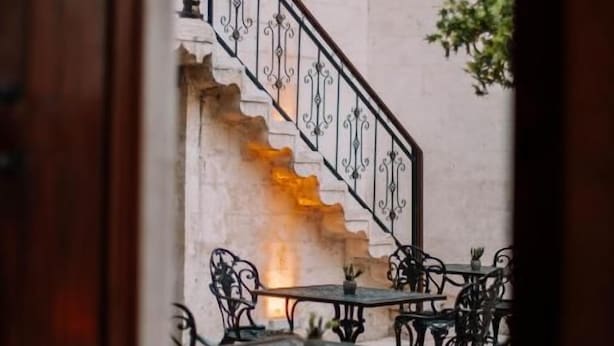 A staircase with ornate railings leading to a seating area with tables and chairs. - HOTEL ESTARA (Şanlıurfa)