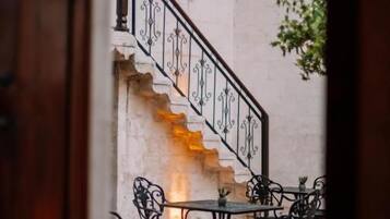 A staircase with ornate railings leading to a seating area with tables and chairs.