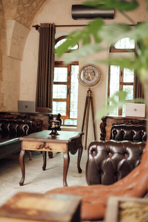 A room with a vintage aesthetic, featuring a leather sofa, a wooden coffee table, and a classic wall clock. - HOTEL ESTARA (Şanlıurfa)