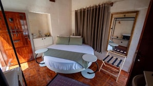 A bedroom with a bed, bedside tables, a mirror, curtains, and a wooden floor. - HOTEL ESTARA (Şanlıurfa)