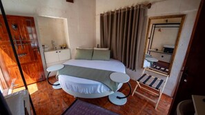 A bedroom with a bed, bedside tables, a mirror, curtains, and a wooden floor. - HOTEL ESTARA (Şanlıurfa)