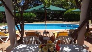 A poolside area with a table, chairs, and umbrellas. - Holiday home with 3 bedrooms (Carvoeiro LGA)
