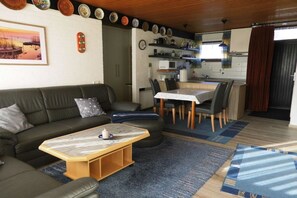 Ein Wohnzimmer mit einer Couch, einem Couchtisch und einem Essbereich mit Stühlen und einem Tisch.
