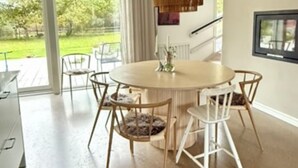 Un comedor moderno con una mesa redonda, sillas blancas y una lámpara colgante.