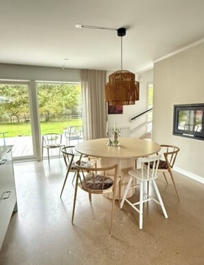 Un espace repas moderne avec une table ronde, des chaises blanches et un luminaire suspendu.