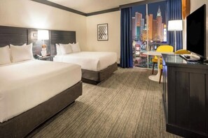Ein Hotelzimmer mit zwei Betten, einem Schreibtisch mit Stuhl, einem Fernseher und Blick auf die Stadt.