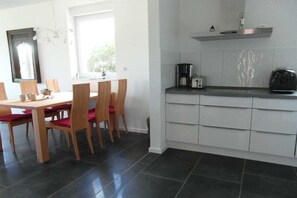 Eine moderne Küche mit Einbauofen, Kaffeemaschine und kleinem Kühlschrank.