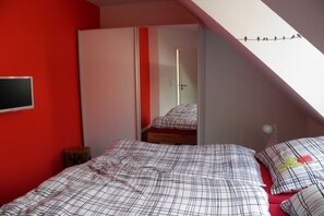 Ein Schlafzimmer mit einem Bett, einem Kleiderschrank und einem Spiegel, der den Raum wiederspiegelt.