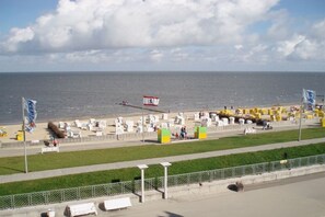 A coastal area with a promenade, a flag, and a row of white structures, possibly a memorial or monument. - Nautilus Penthouse Beach View (Cuxhaven)